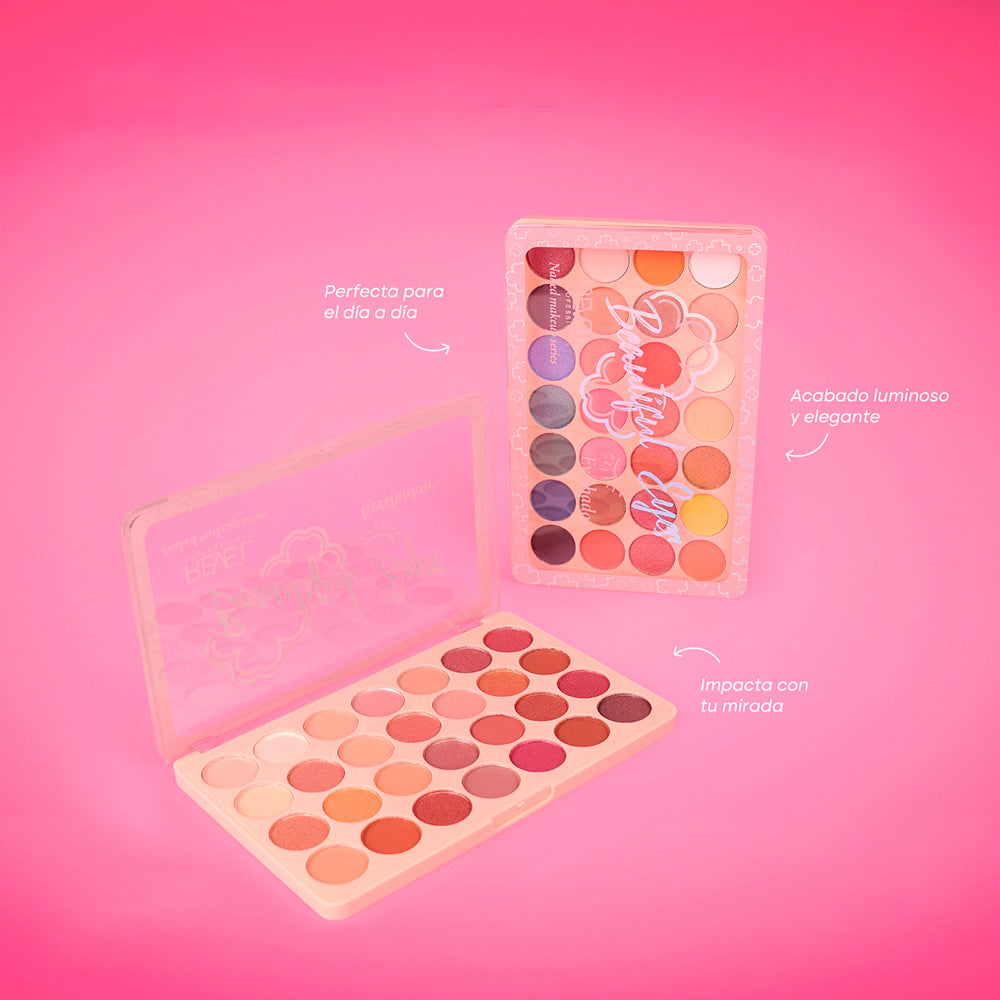Paleta de sombras Reve'l Beautiful Eyes con 28 tonos en acabados mate y luminoso, colores cálidos, rosados y neutros, presentada en estuche rosado con diseño floral