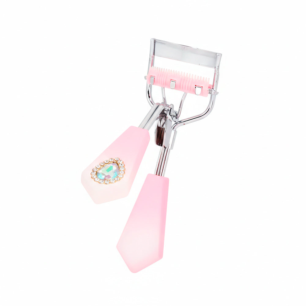 Rizador de pestañas Strass Heart Curl con mango facetado rosa palo degradé, detalle corazón strass y cerdas integradas rosa sobre fondo blanco