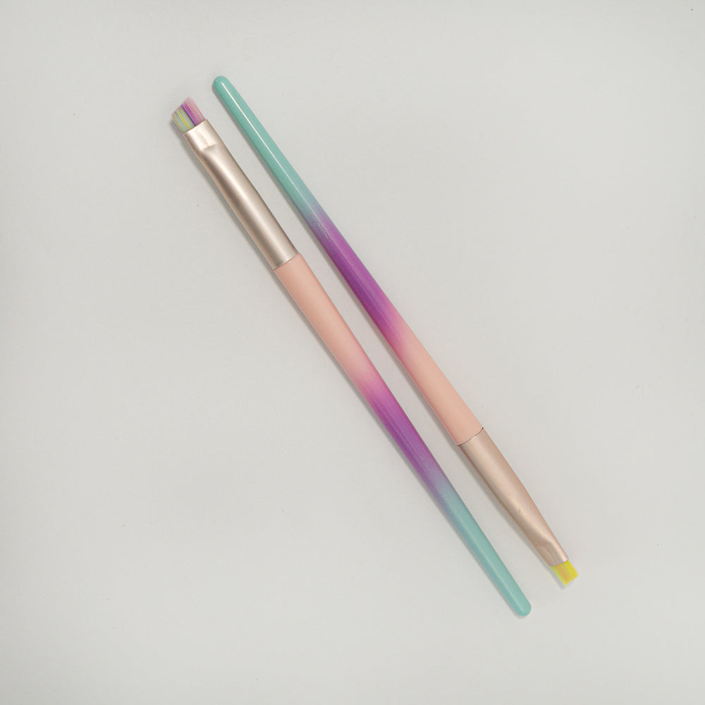 Brocha de delineado punta redonda y abanico cerdas multicolor degradé con mango menta morado y rosa y ferrule rose gold sobre fondo blanco