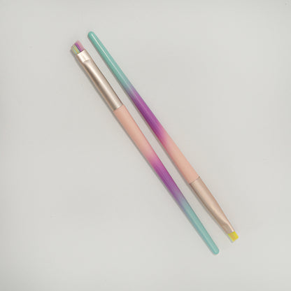 Brocha de delineado punta redonda y abanico cerdas multicolor degradé con mango menta morado y rosa y ferrule rose gold sobre fondo blanco