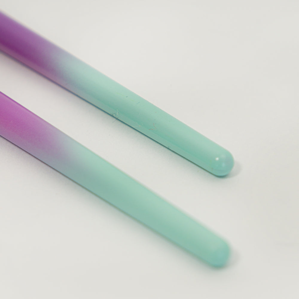 Detalle de la punta redondeada de brocha para sombras con acabado degradado en tonos morado y verde menta