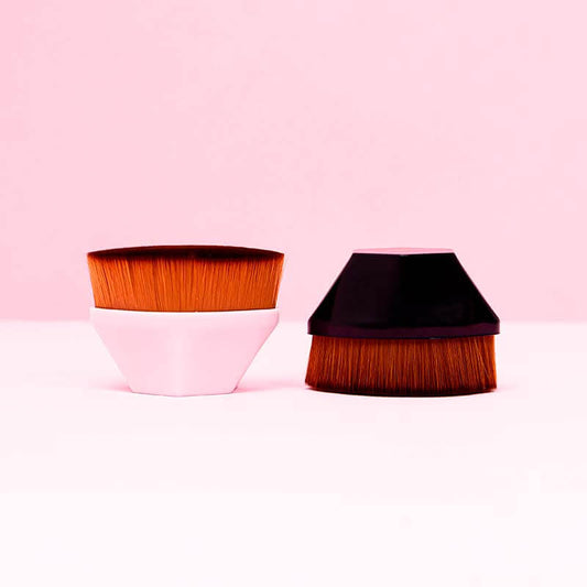 Brocha mágica kabuki de cerdas densas en colores rosa y negro sobre fondo rosa — para base de maquillaje