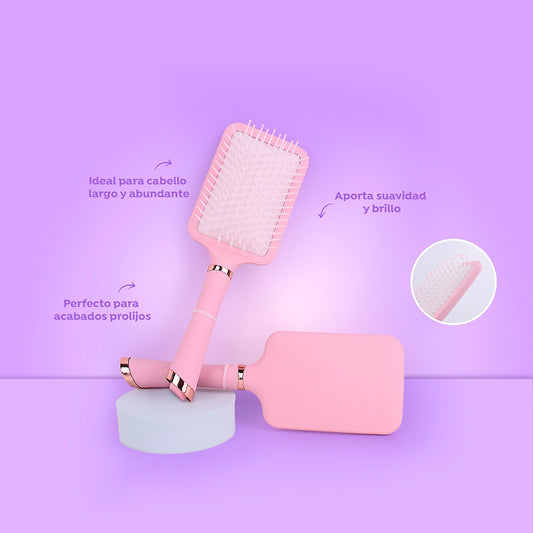 Cepillo paddle Silk Smooth rectangular rosa pastel con cerdas flexibles y detalles rose gold para cabello largo abundante sobre fondo lila