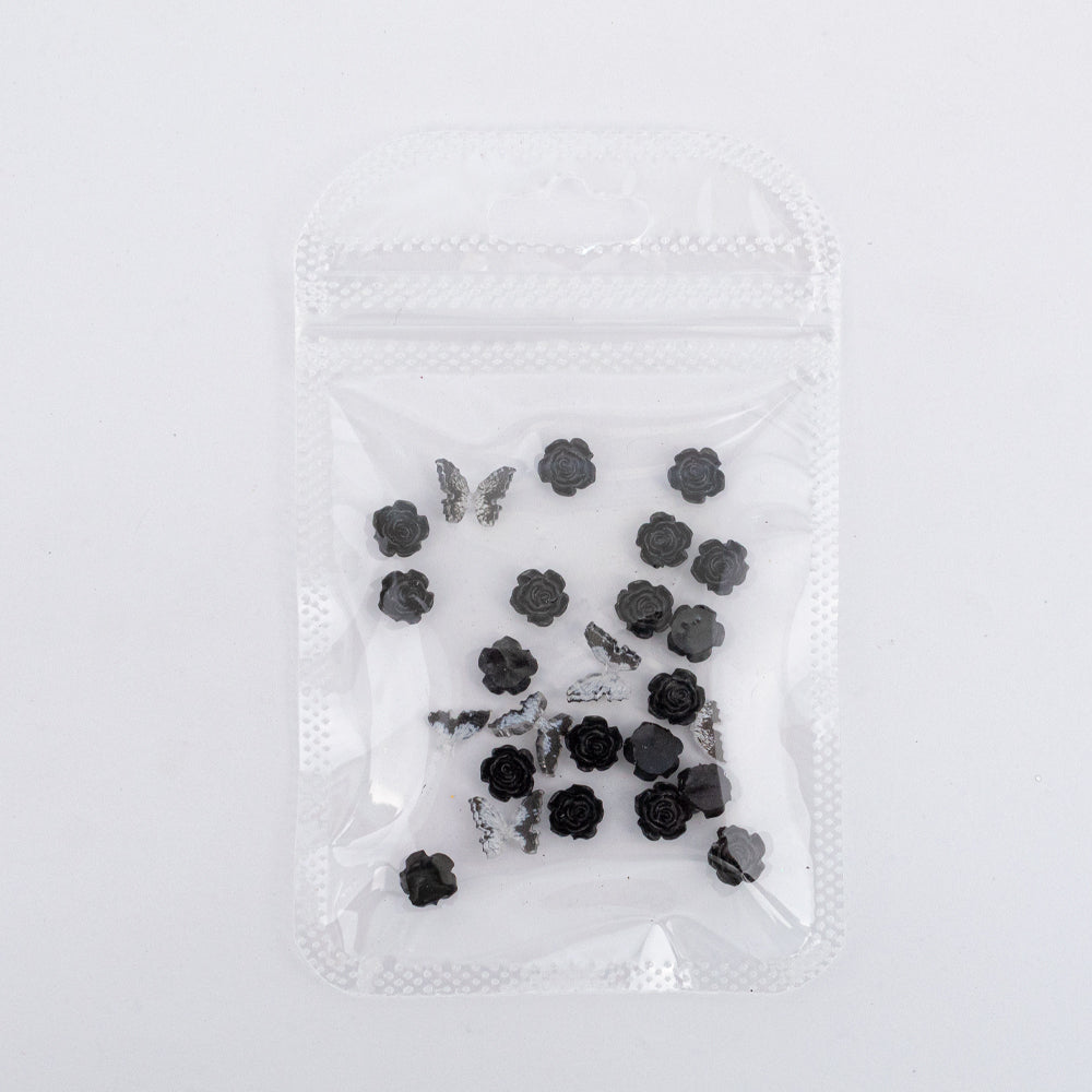 Dijes para uñas Nail Art de rosas y mariposas en resina color negro en bolsa transparente sobre fondo blanco