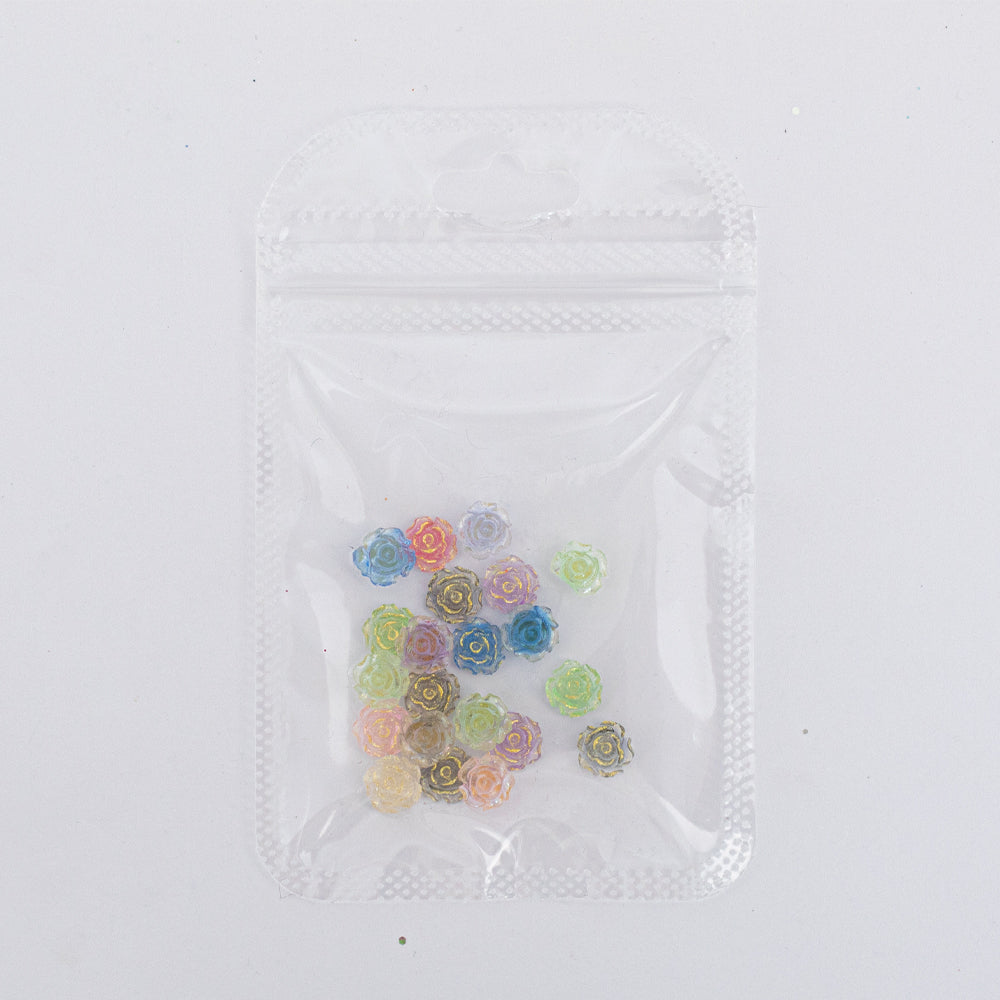 Dijes para uñas Nail Art de rosas multicolor en resina en bolsa transparente sobre fondo blanco