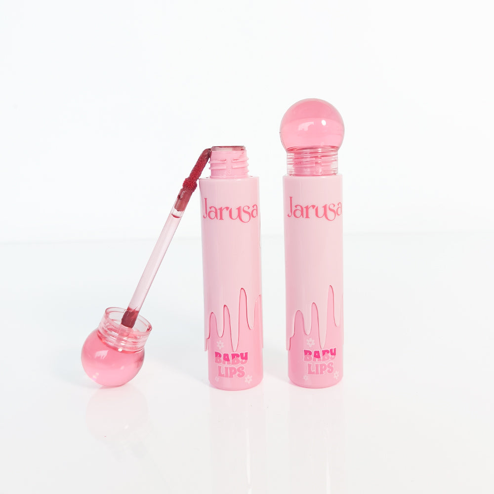 Brillo labial rosa Jarusa Baby Lips con aplicador y envase rosa pastel sobre fondo blanco