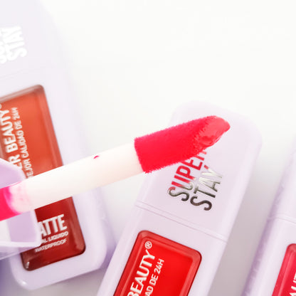 Detalle de aplicador del Labial Líquido Matte Super Stay Waterproof Ever Beauty en tono rojo, acabado aterciopelado matte con productos al fondo