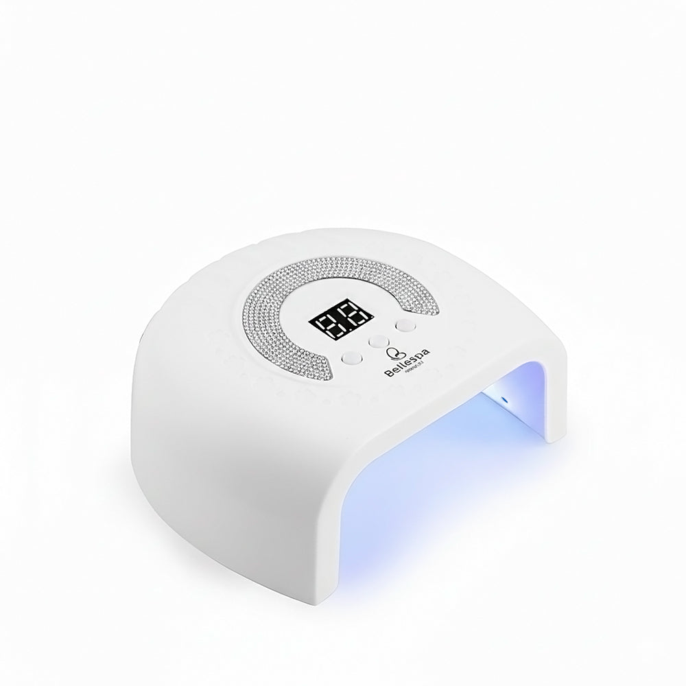 Lámpara UV LED para Uñas con Pedrería Bellespa Cosmetics color blanco con luz LED activa y pantalla digital, vista frontal sobre fondo blanco