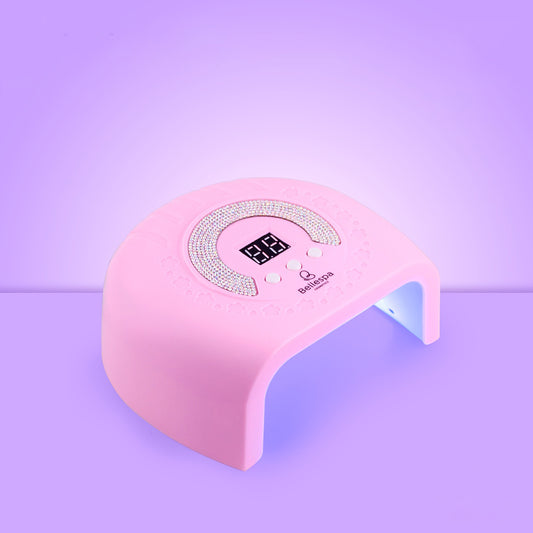 Lámpara UV LED para uñas Bellespa Cosmetics con pedrería en arco, pantalla digital y botones de control, color rosa suave sobre fondo lila