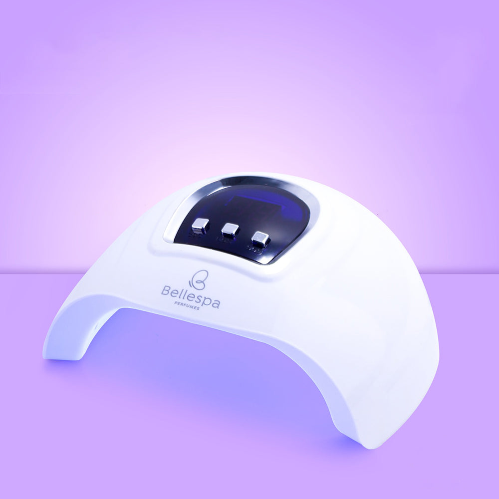 Lámpara UV LED para uñas clásica Bellespa Cosmetics color blanco con pantalla digital y 3 botones de control, sobre fondo lila degradado