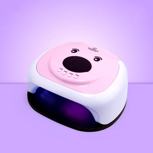 Lámpara UV LED para uñas Bellespa Cosmetics diseño osita en blanco y rosa, panel superior con cara de osita y nariz ovalada, 4 botones de tiempo y base negra con luz UV activa, sobre fondo lila degradado