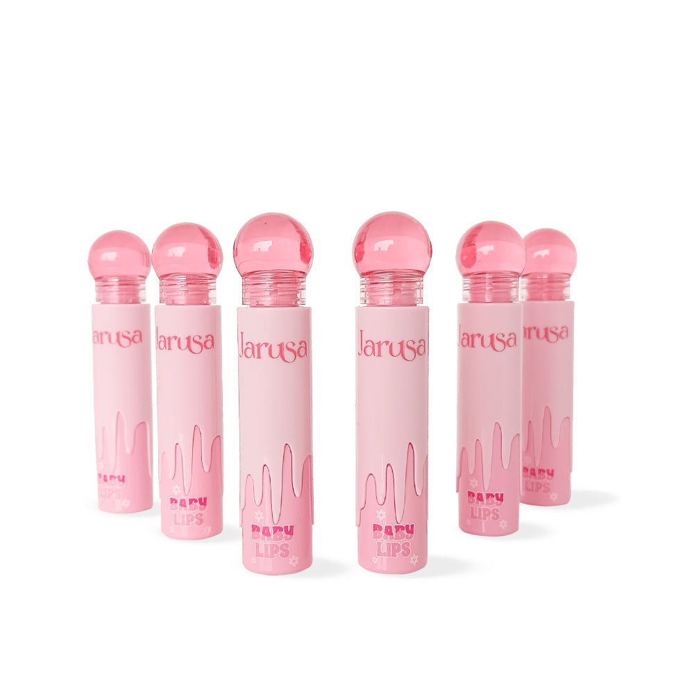 Lip gloss Jarusa Baby Lips con tapa bola rosa y empaque rosa pastel efecto drip, fórmula brillante e hidratante, sobre fondo blanco