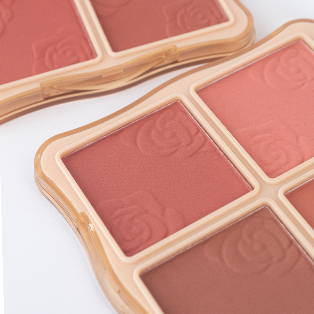 Detalle de textura de la paleta de rubor Hello Perfect Blusher Reve'l con tonos rosados y marrón en relieve de rosas sobre compacto dorado