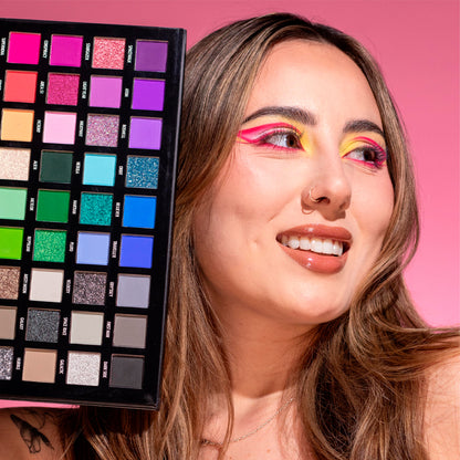 Modelo sosteniendo Paleta Sombras Carnival Interstellar Stacey Marie Reve'l abierta mostrando tonos vibrantes neón glitter y neutros con look colorido