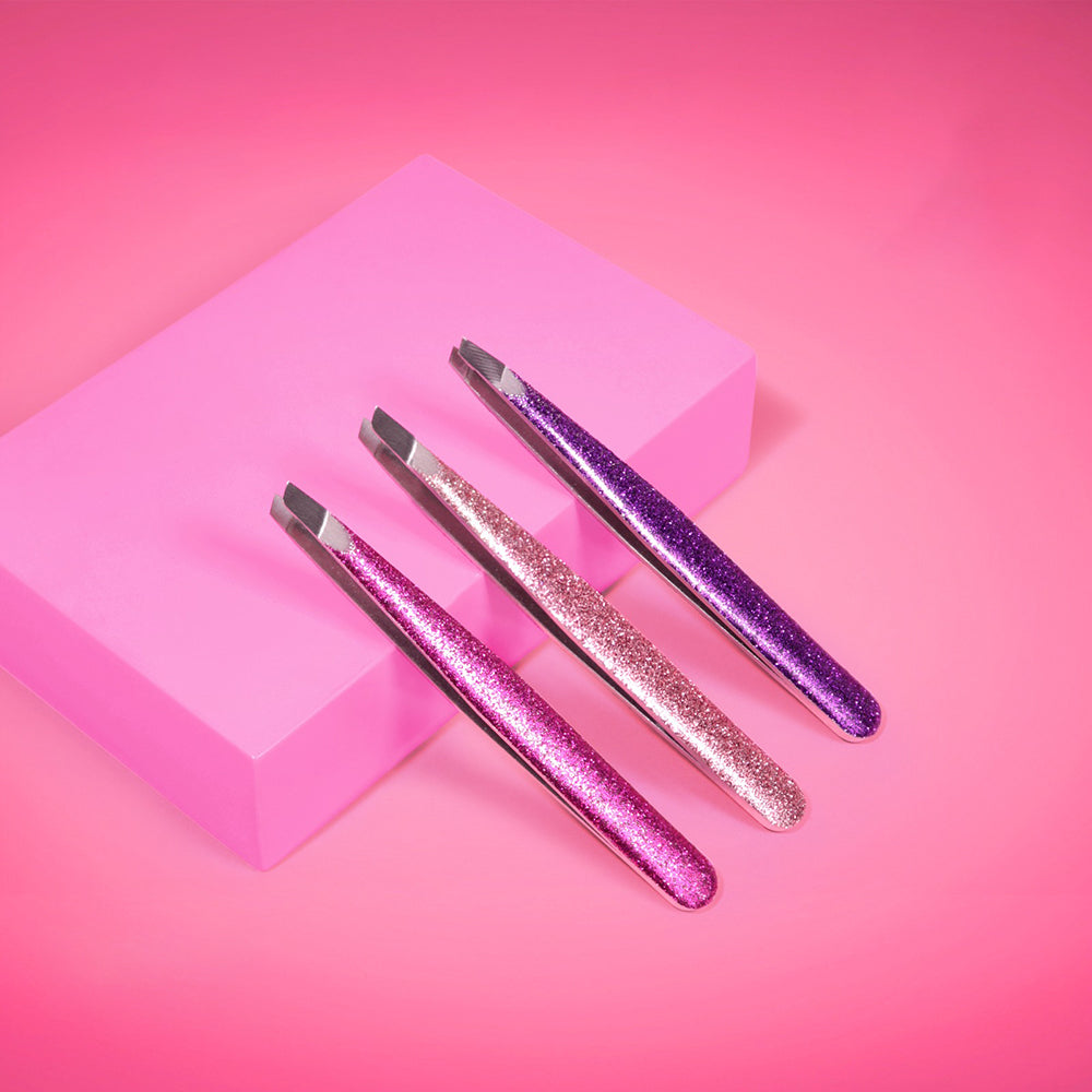 Pinza de cejas punta diagonal Reve'l con mango glitter brillante en tres colores fucsia rosado dorado y morado