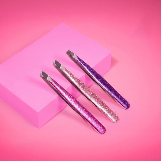 Pinza de cejas punta diagonal Reve'l con mango glitter brillante en tres colores fucsia rosado dorado y morado