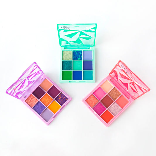 Tres variantes abiertas de la Paleta de Sombras Diamond 9 Tonos Reve'l Professional mostrando tonos vibrantes en púrpura y naranja, verde y azul teal, rosa y coral en compactos transparentes