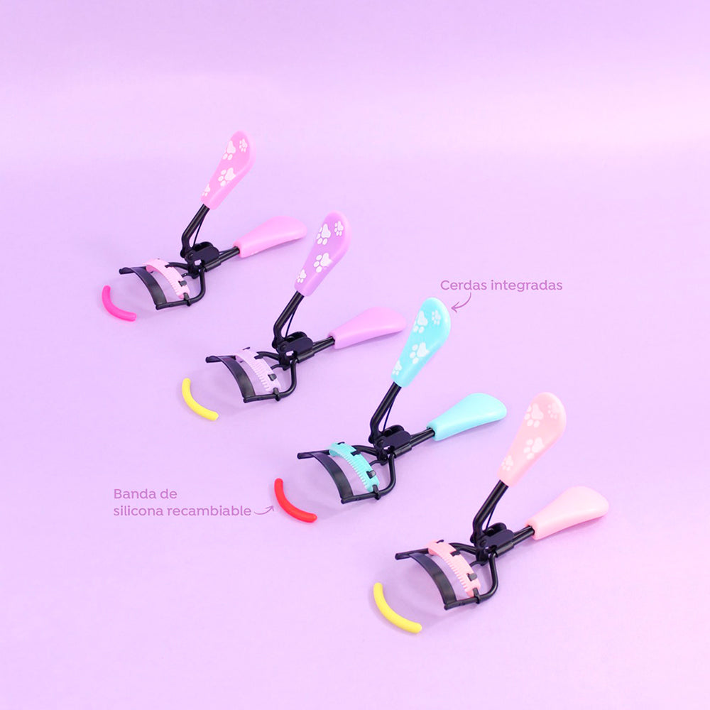 Rizador de pestañas Black Skye Charm con spoolie integrado y banda de silicona recambiable, en colores rosa, menta y durazno con diseño de huellas.
