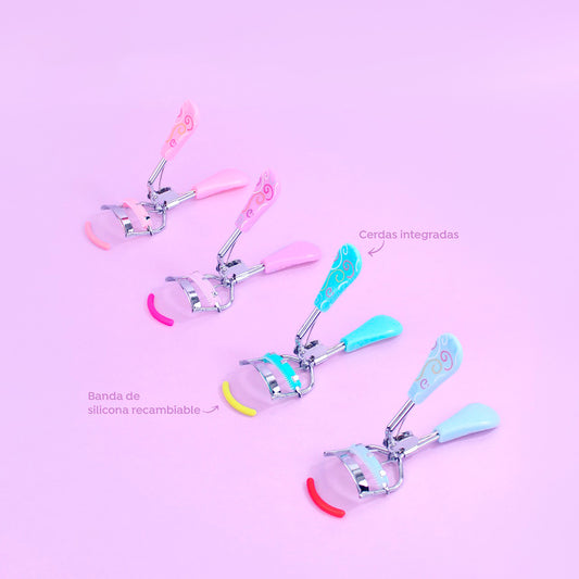 Rizador de pestañas con spoolie y silicona Skye Charm en colores rosa y turquesa con estampados sobre fondo rosa pastel