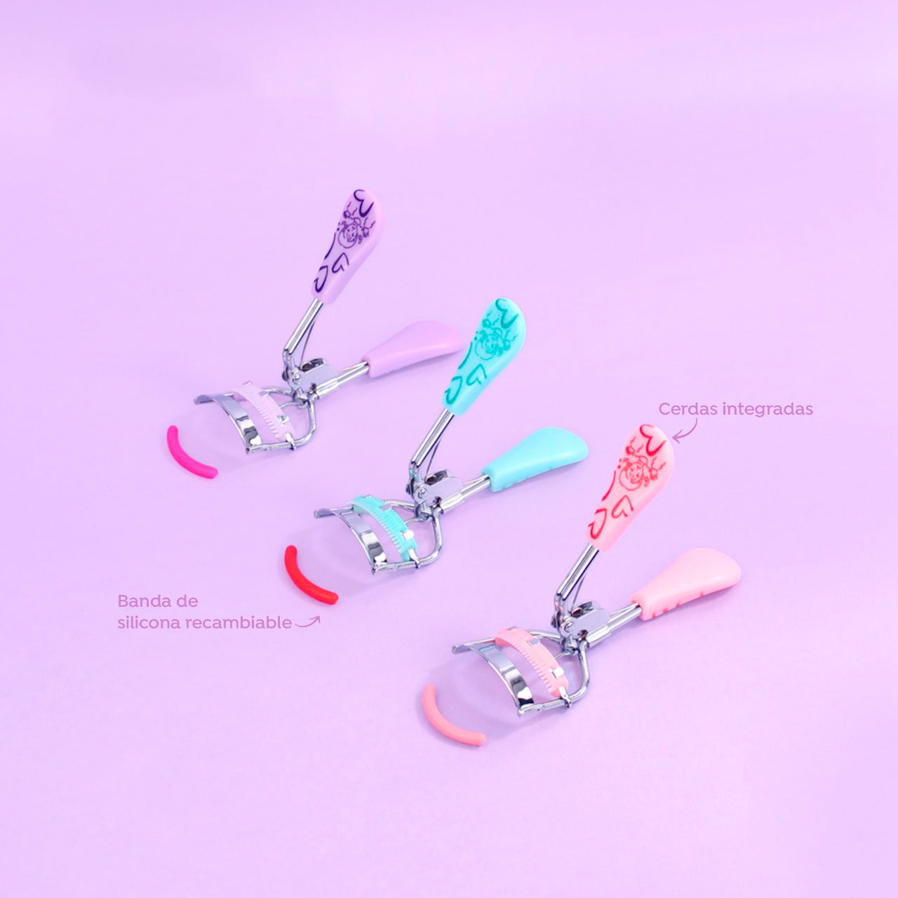 Rizador de pestañas Love Floral Print Curl con mango bicolor estampado de corazones y flores en colores lila, celeste y rosa, cerdas integradas y banda de silicona recambiable sobre fondo lila