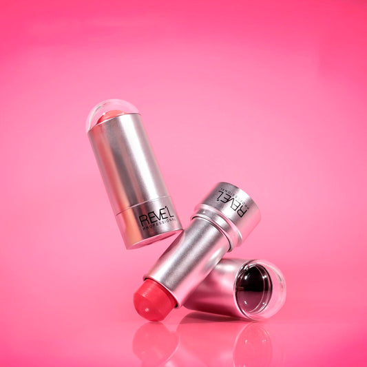 Rubor blush en barra cremoso con estuche plateado y tapa domo transparente en tonos rosa y coral sobre fondo rosa — Reve'l Professional