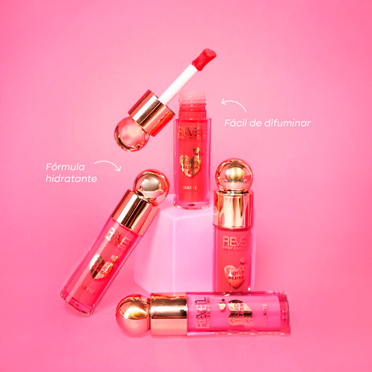 Rubor Liquid Blush Matte con aplicador doe-foot y tapa dorada en múltiples tonos rosa y coral sobre fondo rosa — Reve'l Professional