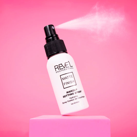 Sellador de maquillaje Matte Finish Hydrating Setting Spray Reve'l Professional en envase blanco con tapa negra sobre fondo fucsia