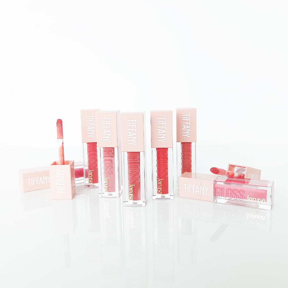 Tiffany Gloss lip gloss oil ultra ligero Jarusa en tonos rojo y rosa, envase cuadrado transparente con tapa nude rosada